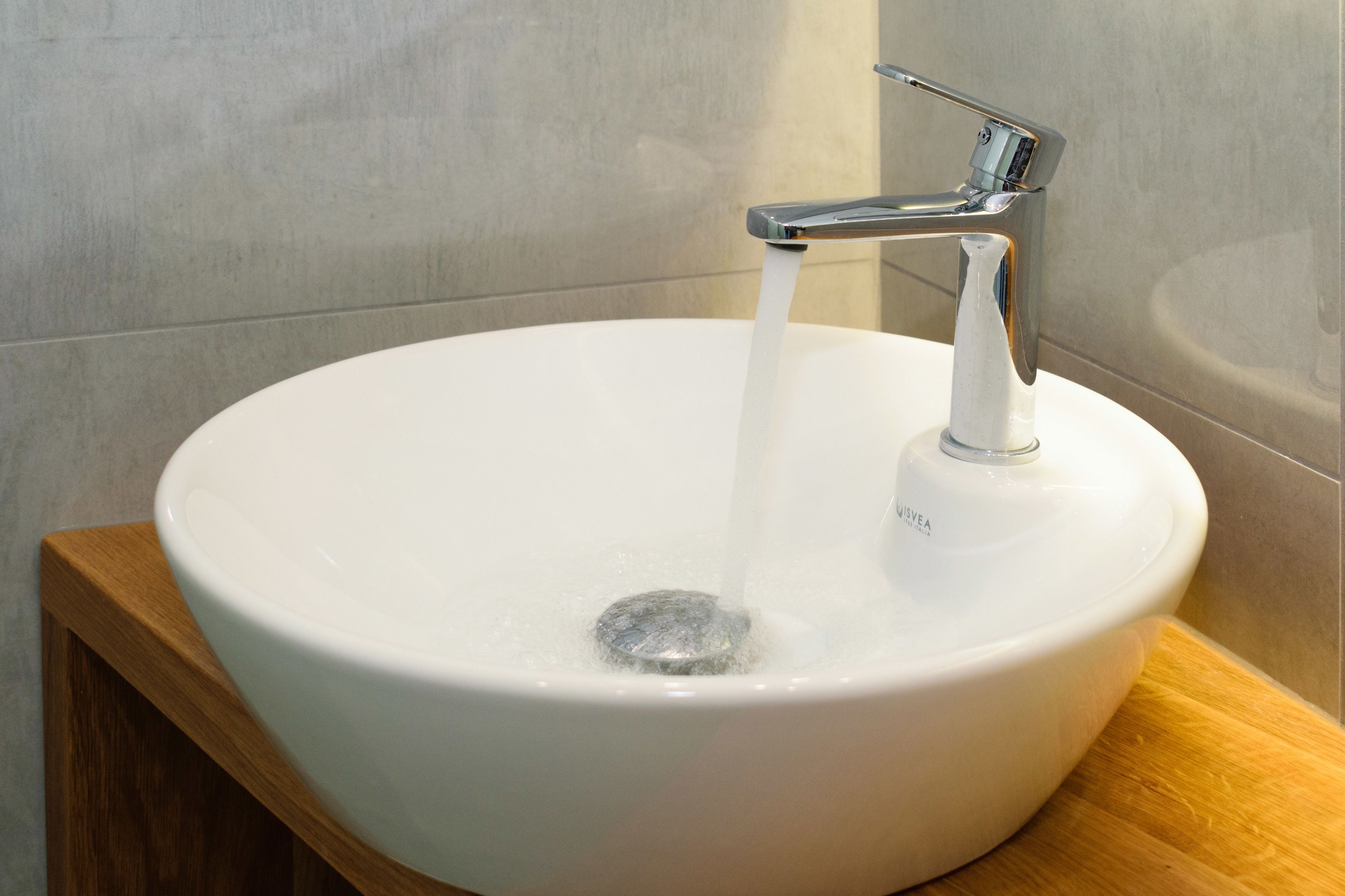 A white ceramic sink with a modern faucet, set against a tiled wall.