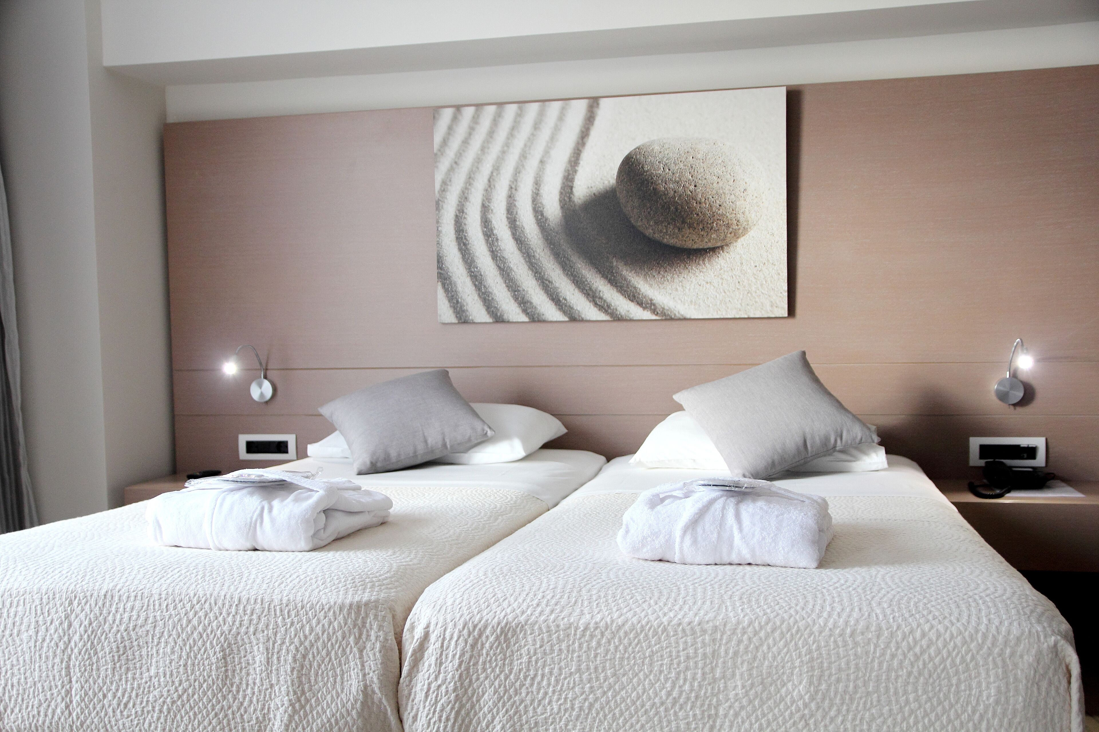A hotel room with two beds, a large artwork on the wall, and bedside lamps.