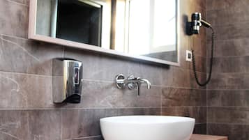 A bathroom with a white sink, a mirror, a towel rack, and a handheld showerhead.