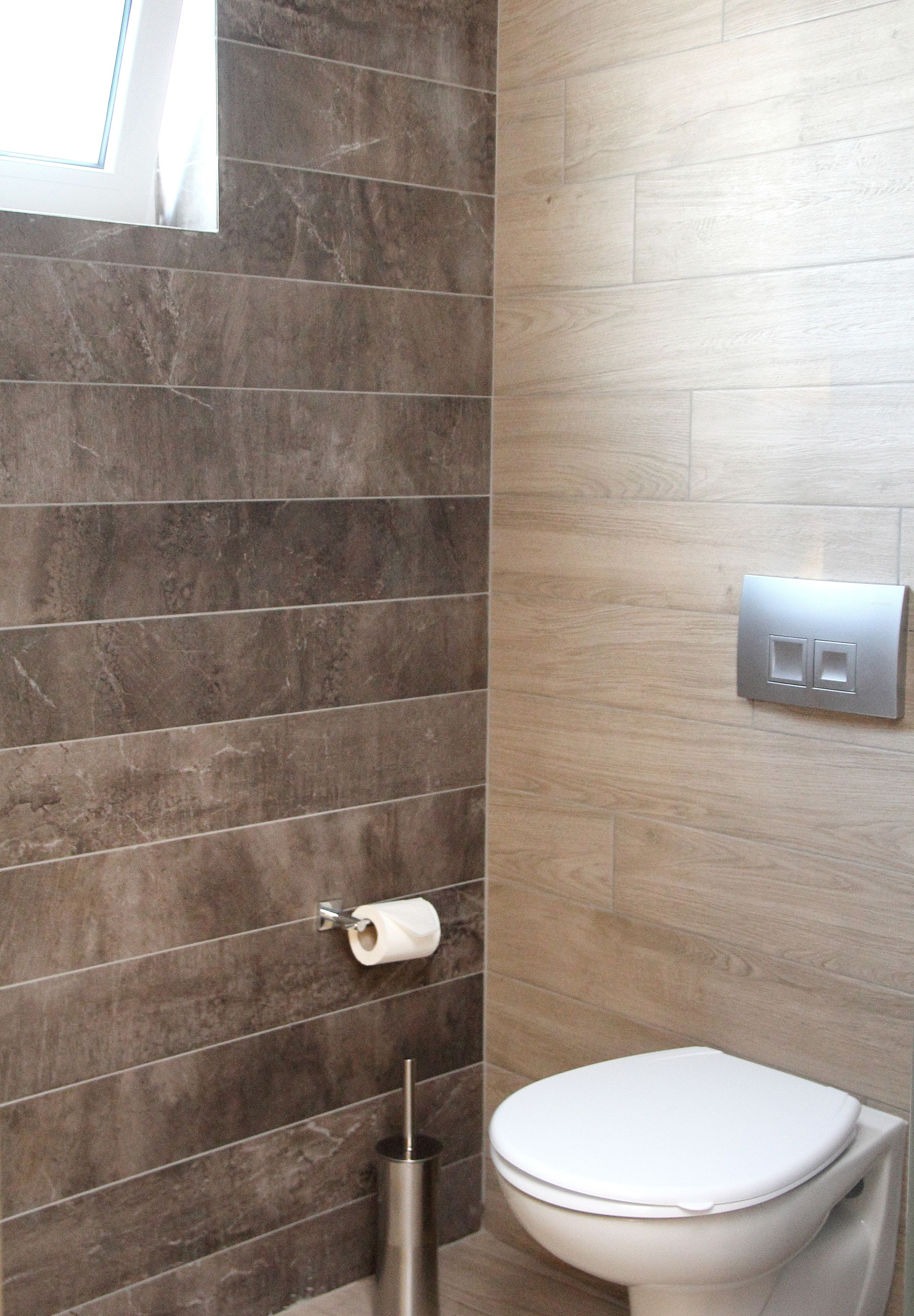 Een badkamer met een toilet, een handdroger en een lichtschakelaar aan de muur.