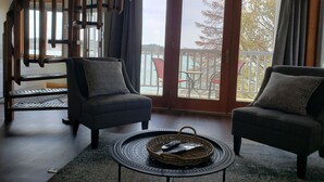 A living room with two armchairs, a small round table with a basket, and a wooden spiral staircase. - Snug Harbor Inn (Sturgeon Bay)