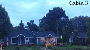 A row of cabins with a dock and a calm body of water in the foreground. - Snug Harbor Inn (Sturgeon Bay)