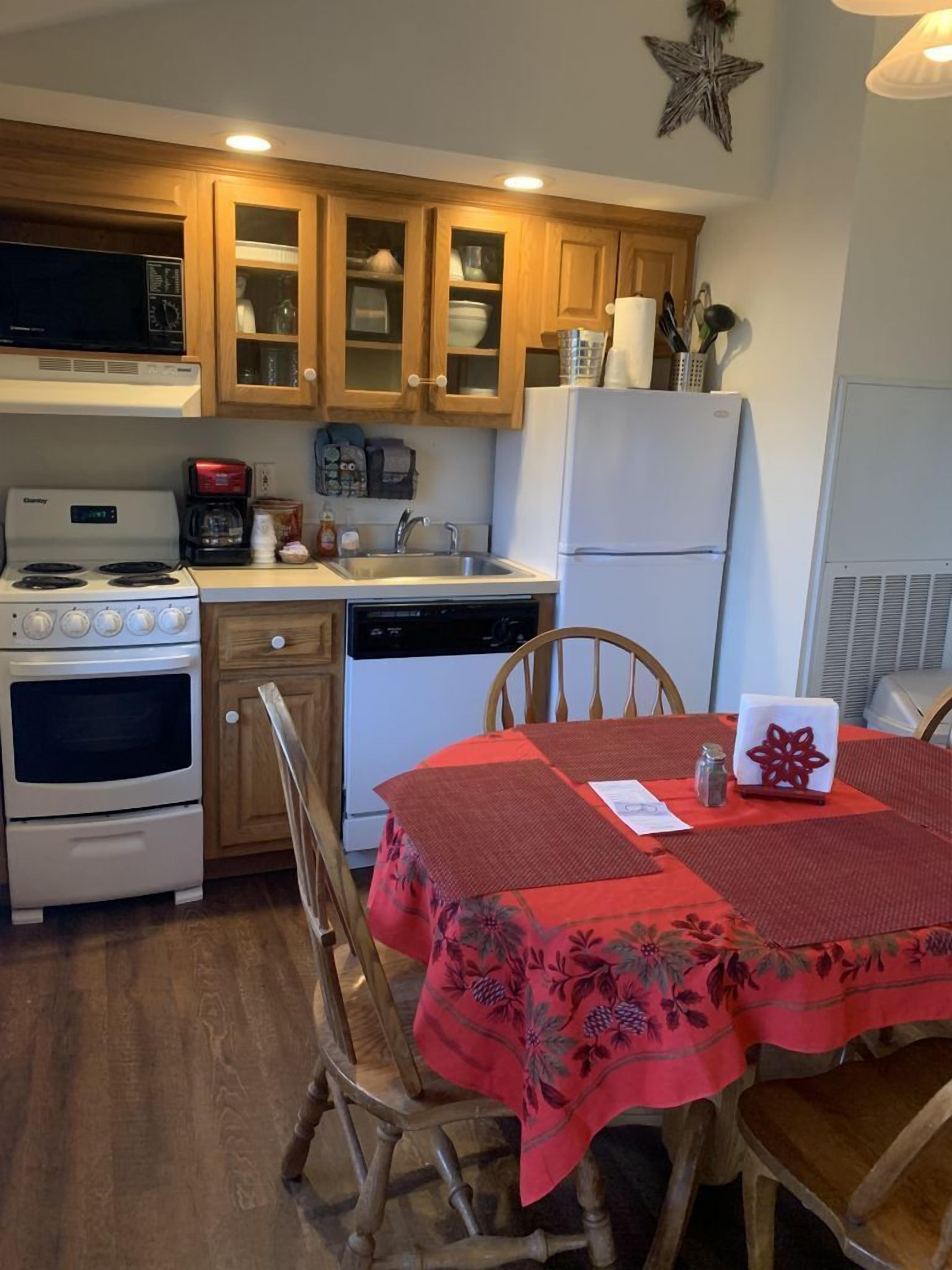 A compact kitchen with wooden cabinets, a microwave, stove, and refrigerator.