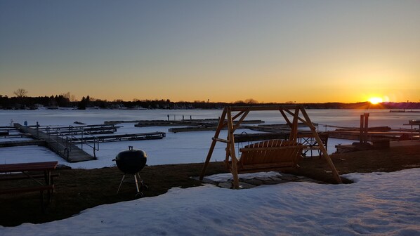 A frozen outdoor area with a grill, wooden swing set, and picnic tables.