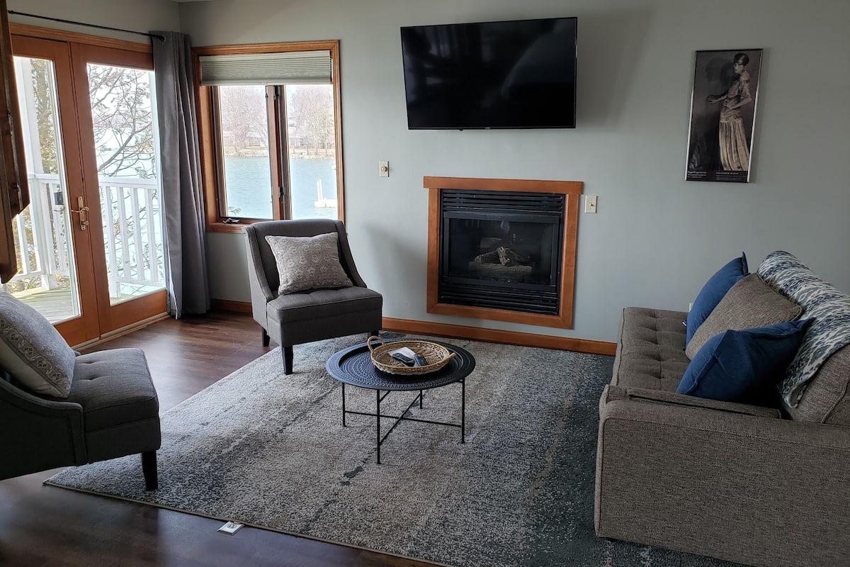 A living room with a fireplace, a television, and a painting on the wall.