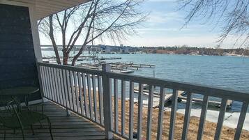 A wooden deck with a railing, a table, and a chair.