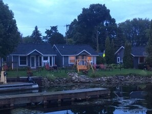 A row of cabins with a dock and a calm body of water in the foreground. - Snug Harbor Inn (Sturgeon Bay)