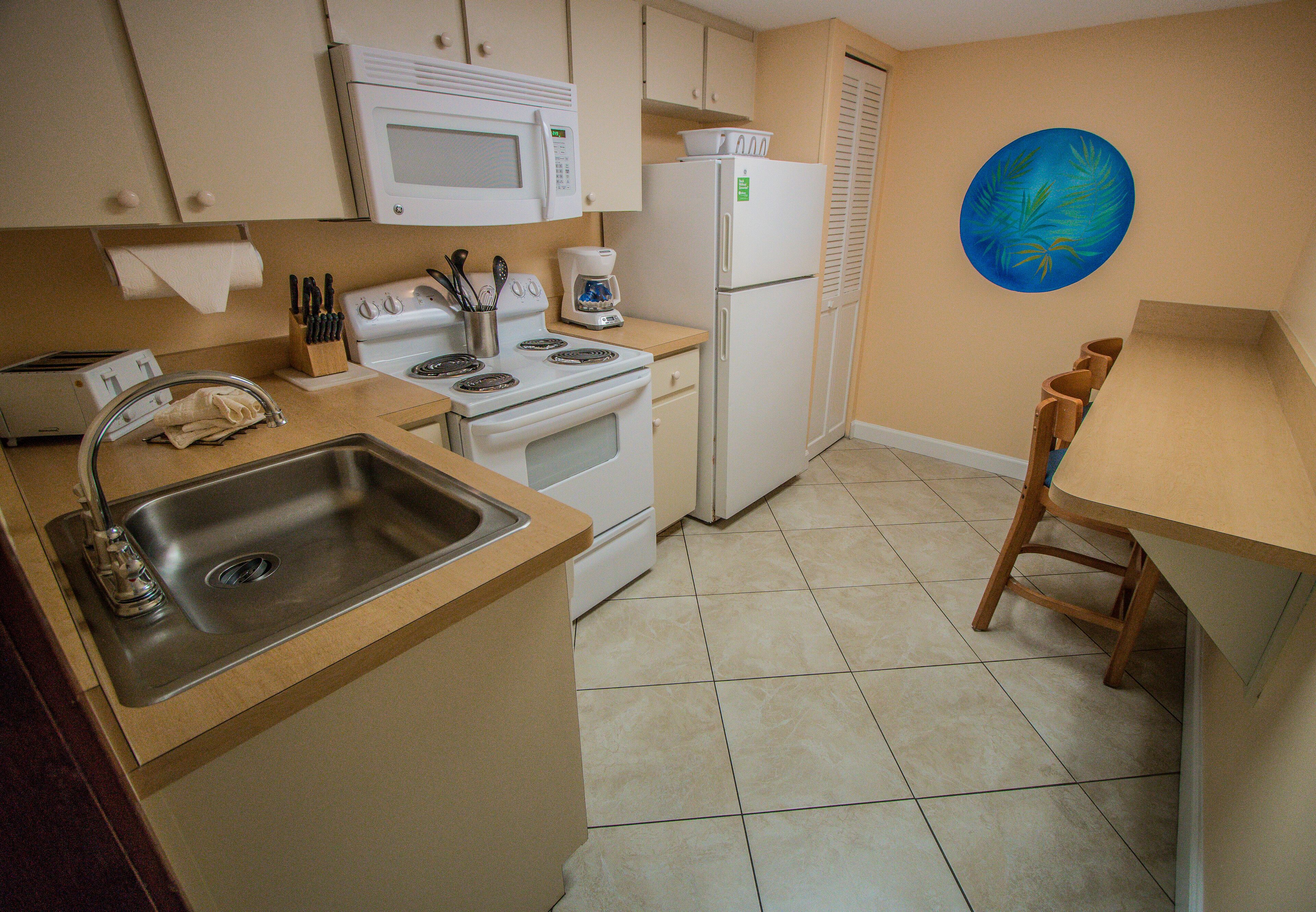A compact kitchen with a sink, stove, microwave, and refrigerator.