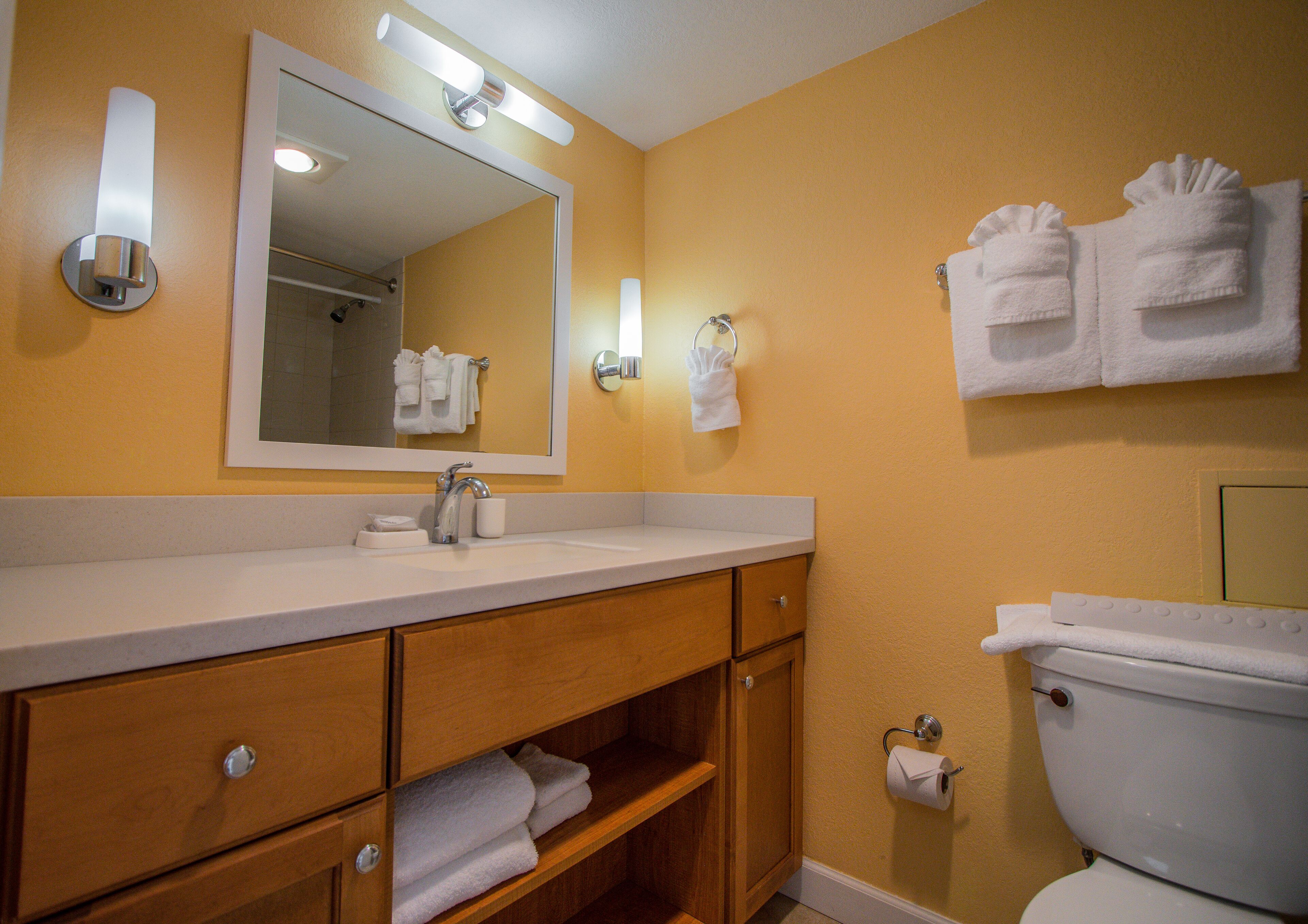 Ein Badezimmer mit Waschbecken, Spiegel, Handtuchhalter und Toilette.