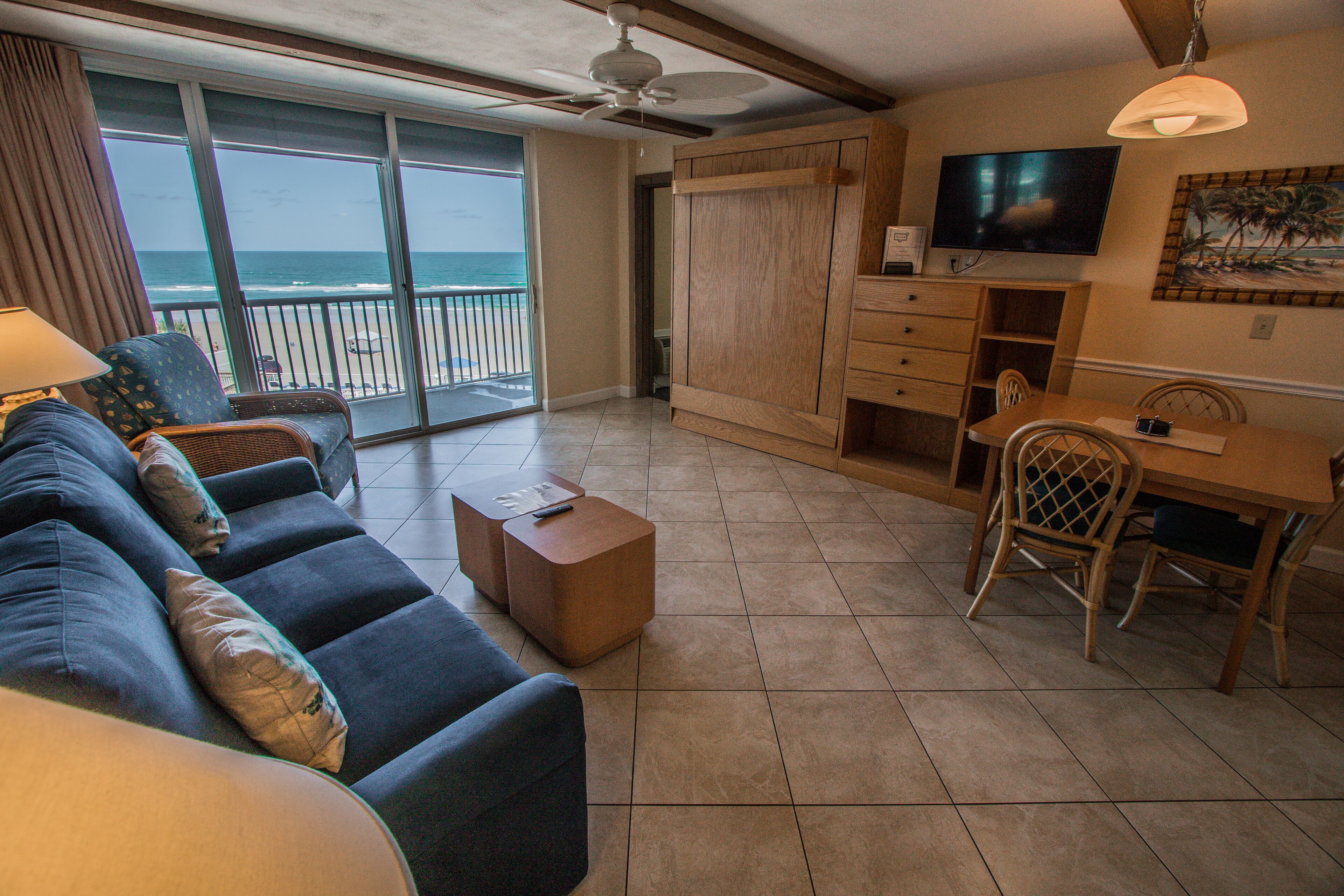 A living room with a sofa, a wooden dining table, and a television.