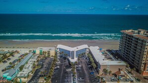 A hotel with a parking lot, beach view, and ocean in the background. - Sea Club IV (Daytona Beach Shores)