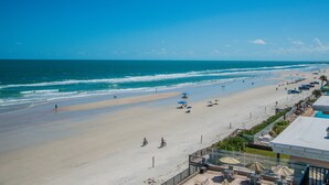 A beach with a clear sky, a sandy shore, and a few umbrellas and chairs. - Sea Club IV (Daytona Beach Shores)