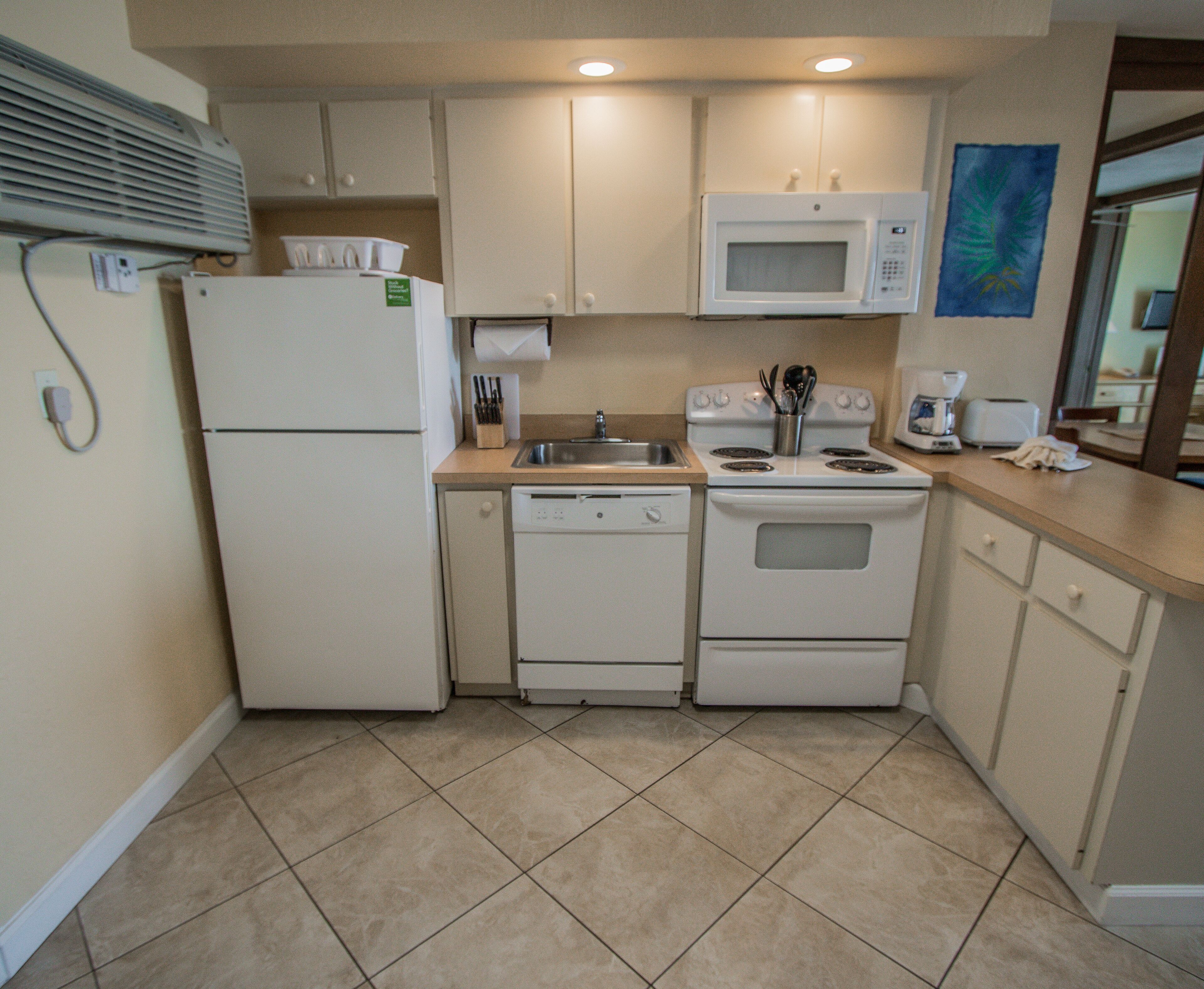 A compact kitchen with a refrigerator, microwave, stove, and dishwasher.