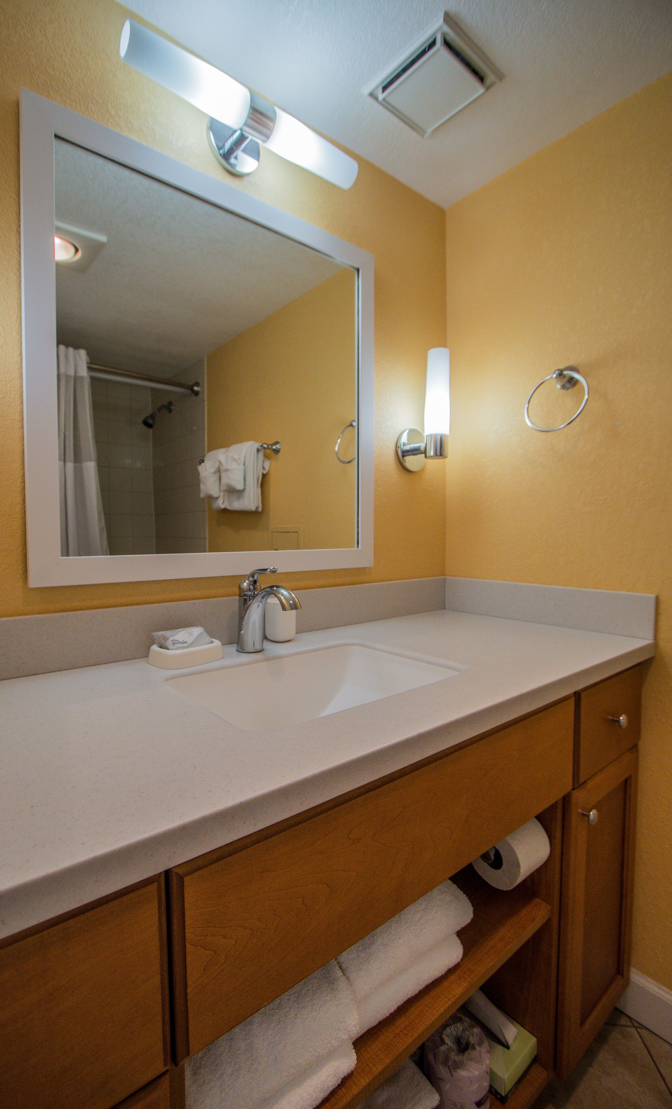 A bathroom with a white sink, a mirror, a towel rack, and a shower curtain.