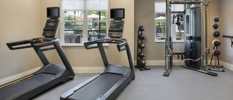 A fitness room with treadmills, a weight machine, and exercise balls.