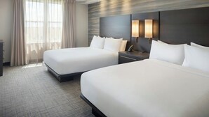 A hotel room with two beds, a large window with curtains, a wall-mounted lamp, and a nightstand. - Residence Inn Tampa Suncoast Parkway at NorthPointe Village (Lutz)