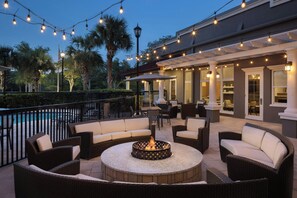 An outdoor patio area with a fire pit, wicker furniture, and string lights. - Residence Inn Tampa Suncoast Parkway at NorthPointe Village (Lutz)