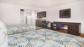 Un dormitorio con dos camas, un escritorio y una kitchenette.
