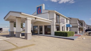 A motel with a prominent '6' sign, a covered entrance, and a parking lot. - Motel 6 Lancaster, TX - DeSoto - Lancaster (Lancaster)