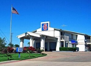 A 6-star motel with a prominent '6' sign, a flagpole with the American flag, and an 'ENTER' sign indicating the entrance.
