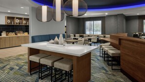 A modern hotel lobby with a central island bar, seating area, and a reception desk. - SpringHill Suites Lehi at Thanksgiving Point (Lehi)