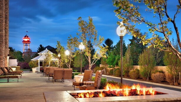 An outdoor patio with stone seating, a fire feature, and a water tower in the background. - SpringHill Suites Lehi at Thanksgiving Point (Lehi)