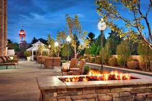 An outdoor patio with stone seating, a fire feature, and a water tower in the background. - SpringHill Suites Lehi at Thanksgiving Point (Lehi)