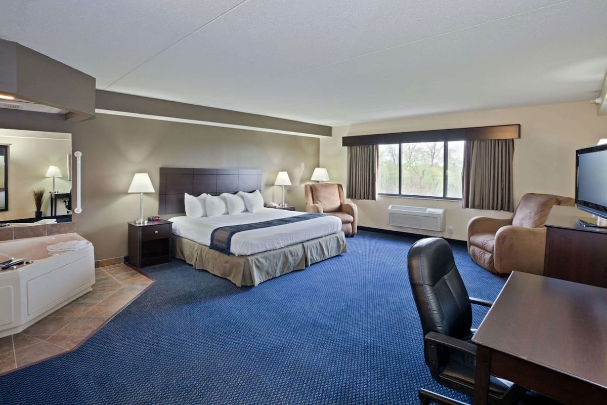Una habitación de hotel con una cama grande, un escritorio, una silla, un televisor y una ventana.