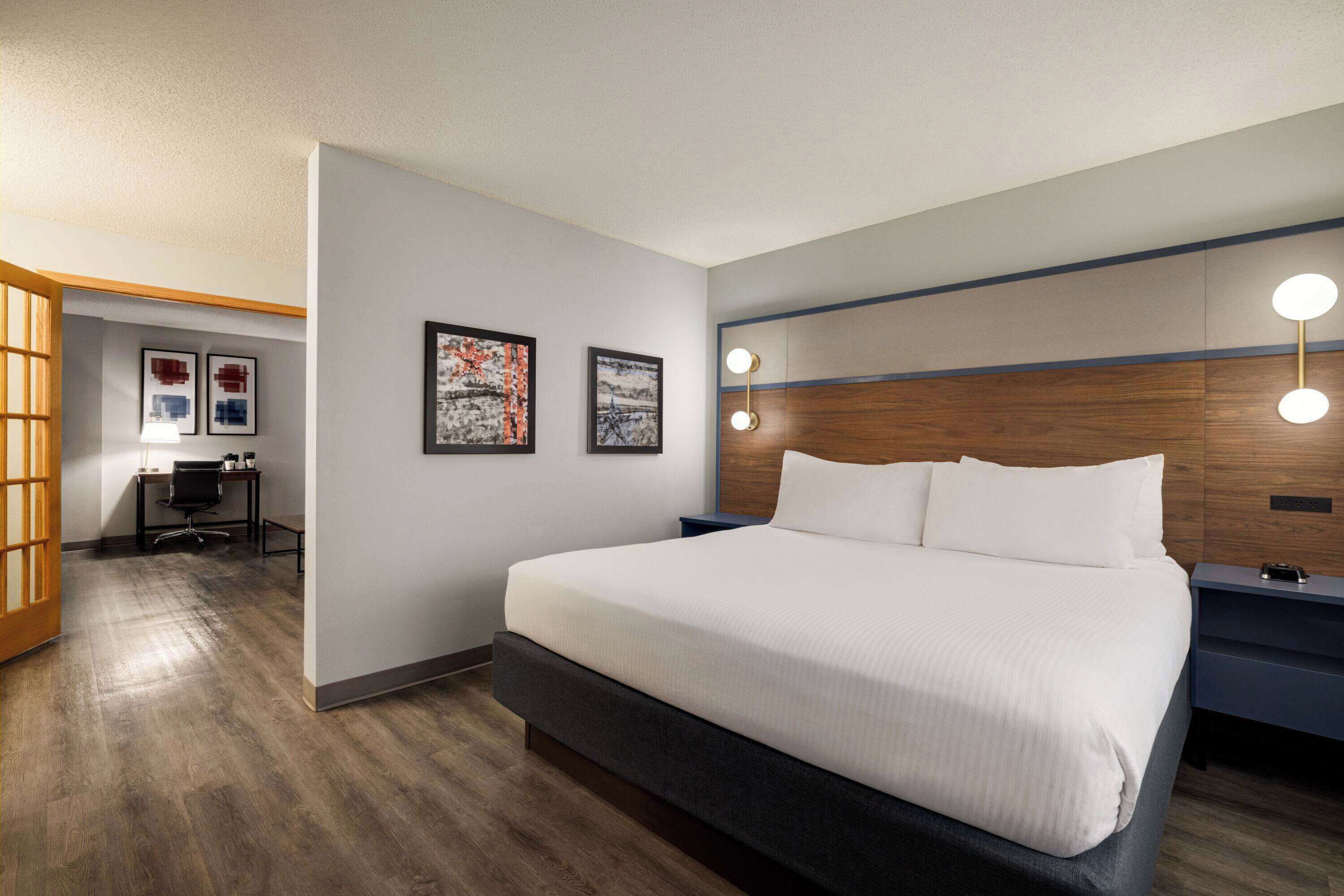 A modern hotel room with a large bed, a desk, and a chair.
