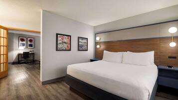 A modern hotel room with a large bed, a desk, and a chair.