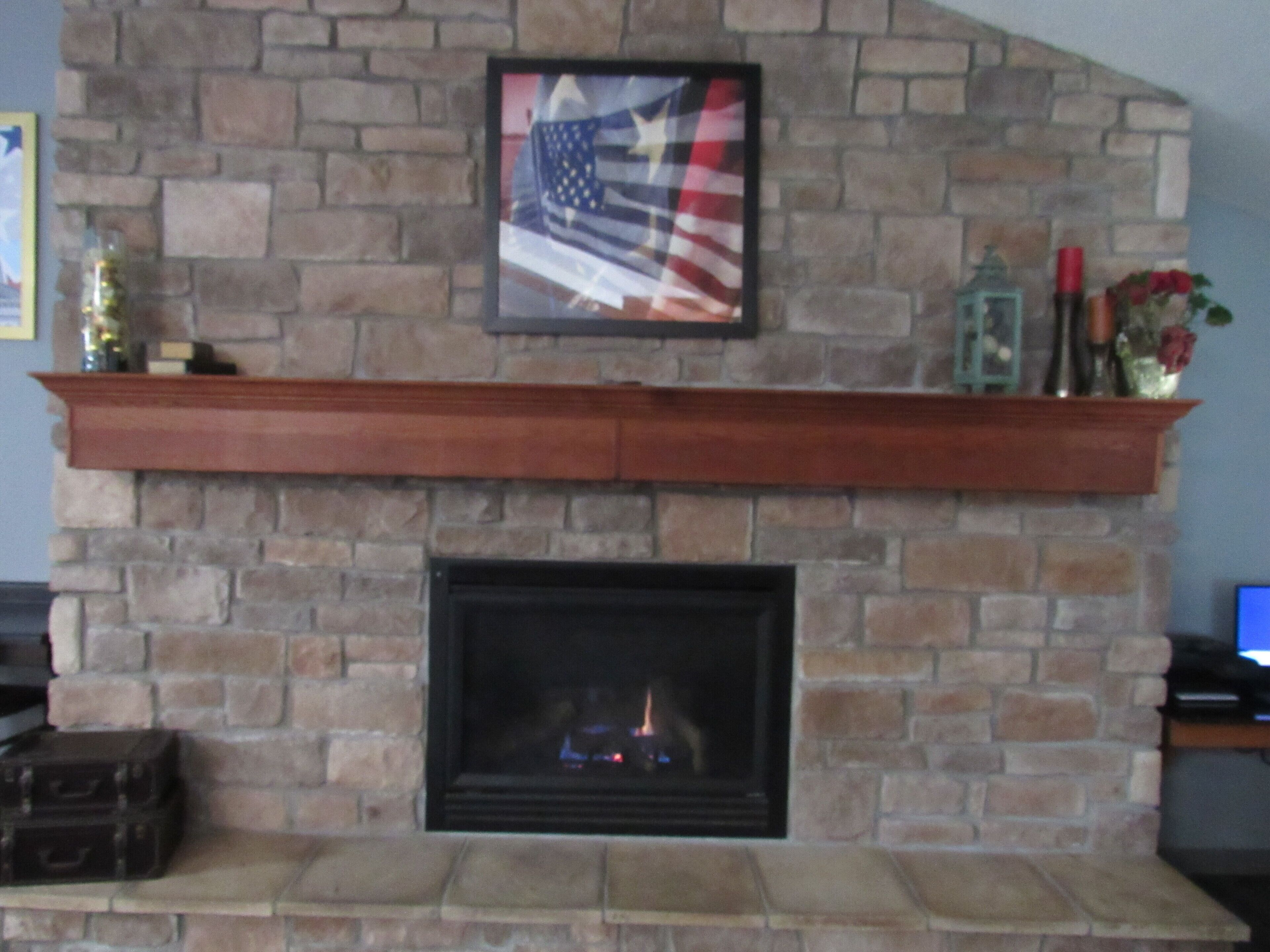 A stone fireplace with a framed American flag above it.
