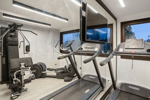 Una palestra moderna con tapis roulant, macchinari per pesi e un ampio specchio.