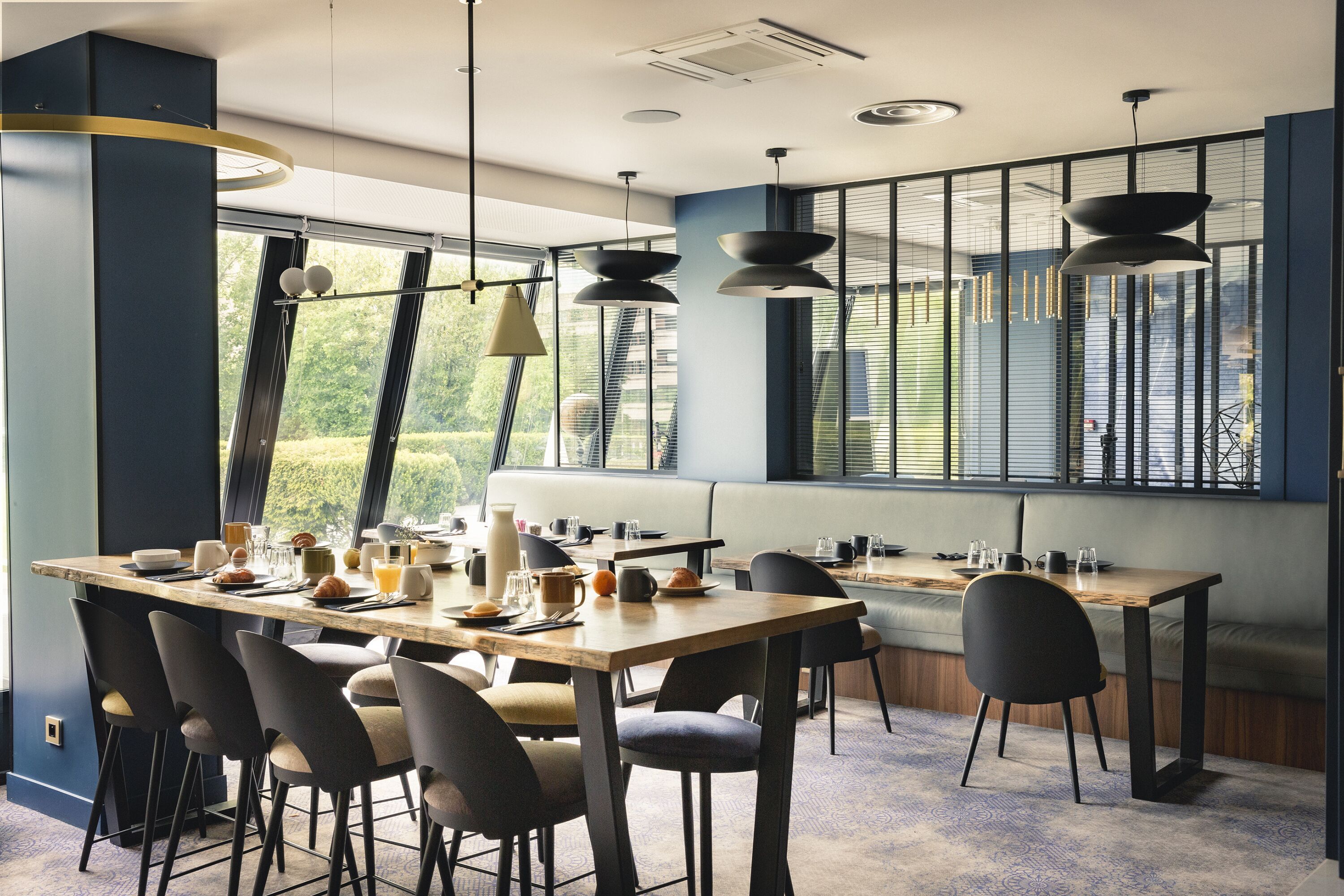 A modern dining area with a long table, multiple chairs, and pendant lighting.
