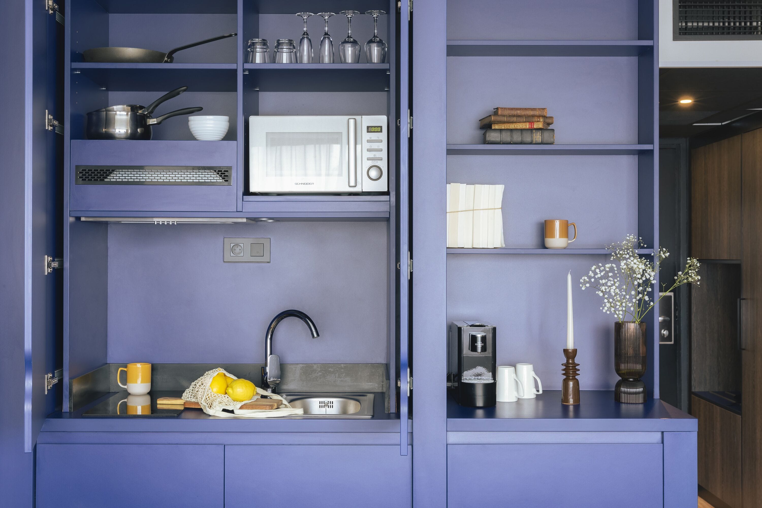 Een kleine keuken met een inbouwmagnetron, een spoelbak en een klein aanrecht.