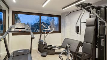 A gym with a treadmill, elliptical, and weight machine.