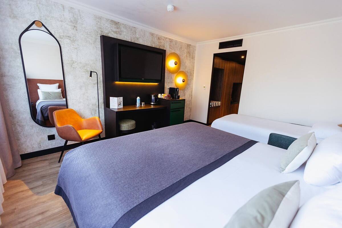 Une chambre d’hôtel comprenant un lit, un bureau avec une chaise, une télévision et un miroir.
