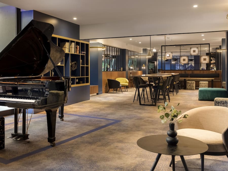 Un interior moderno con un piano de cola, una zona de bar y diversas disposiciones de asientos.