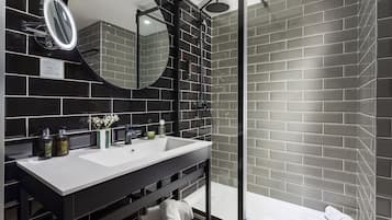 Un baño moderno con diseño de baldosas blanco y negro, un espejo grande, un lavabo y una zona de ducha.