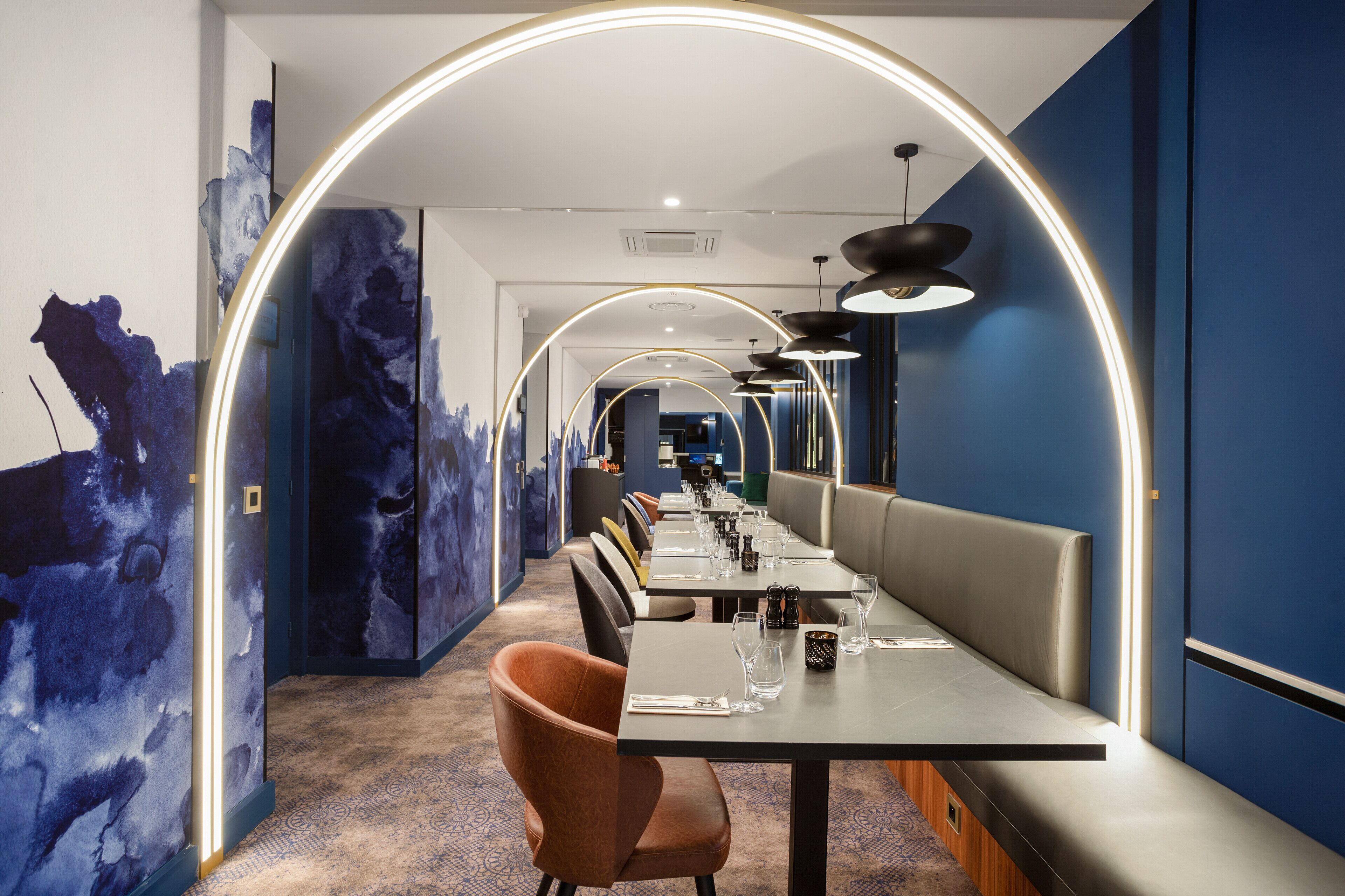 Ein modernes Restaurant mit einer langen Theke, Sitzgelegenheiten und einem einzigartigen Deckenstil.