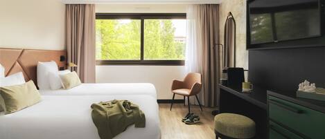 Una habitación de hotel con cama, escritorio, silla y televisor.