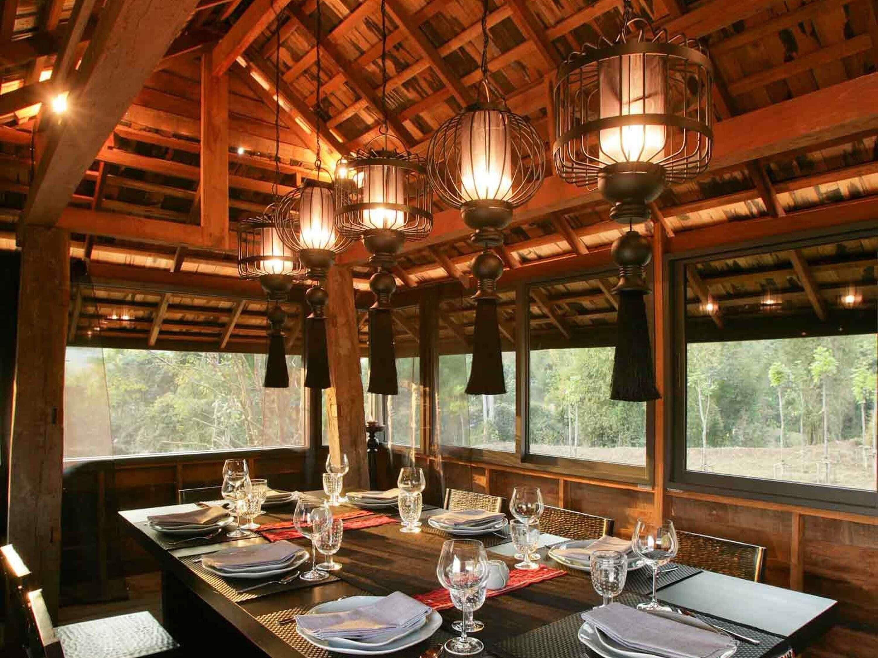 Un comedor con techo de madera, ventanas amplias y varias lámparas colgantes.