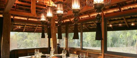 Un espace repas doté d’un plafond en bois, de grandes fenêtres et de plusieurs luminaires suspendus.