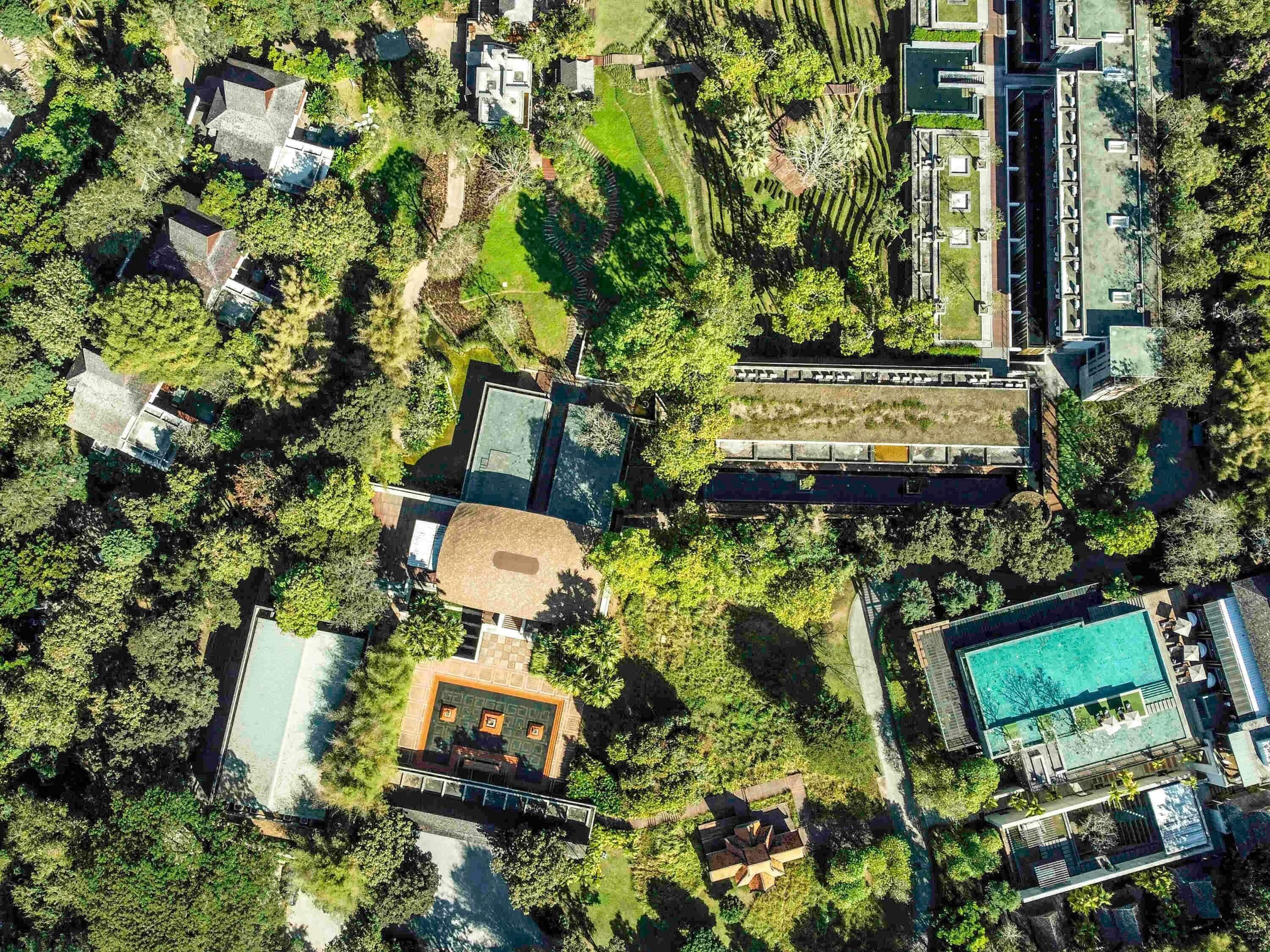 An aerial view of a resort with multiple buildings, a swimming pool, and lush greenery.