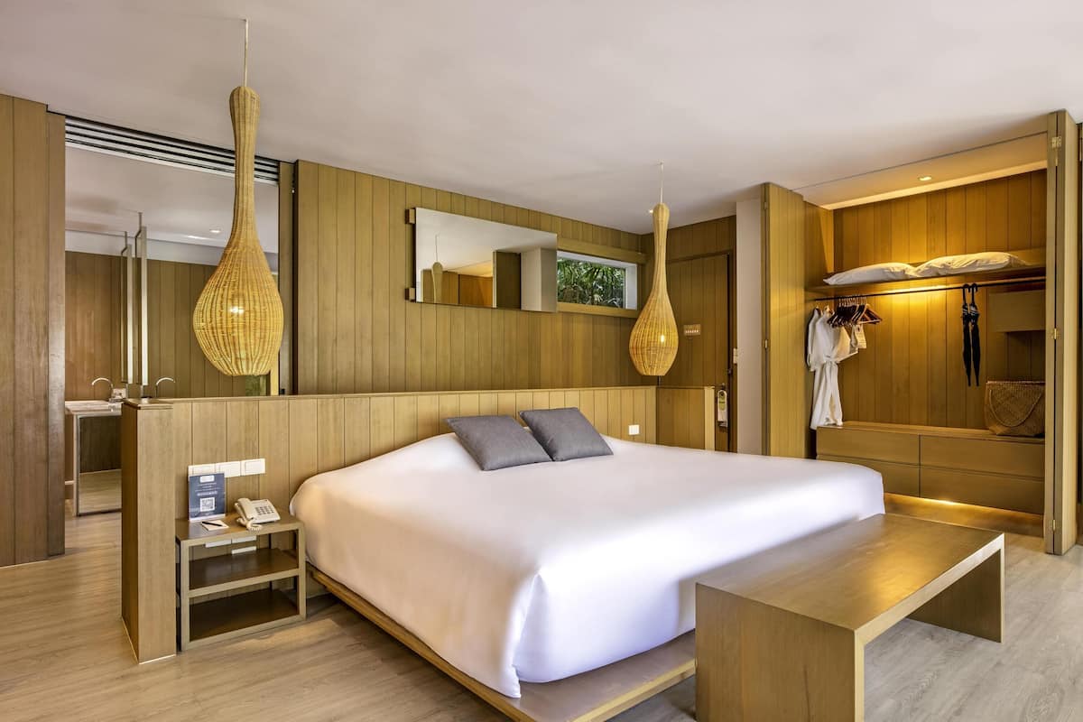 Ein modernes Hotelzimmer mit einem großen Bett, Nachttischen, einem Schreibtisch und einem Kleiderschrank.
