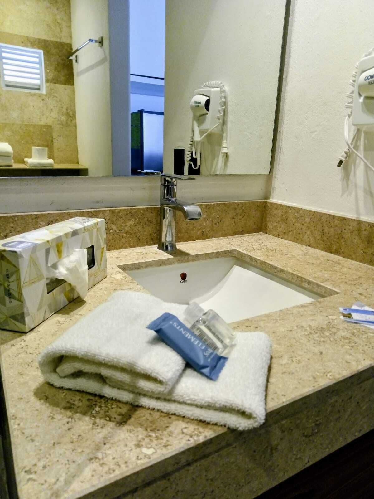 A hotel bathroom with a sink, towel, and toiletries.