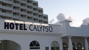 Un hotel llamado "HOTEL CALYPSO" con una fachada moderna, grandes ventanales y una entrada destacada.