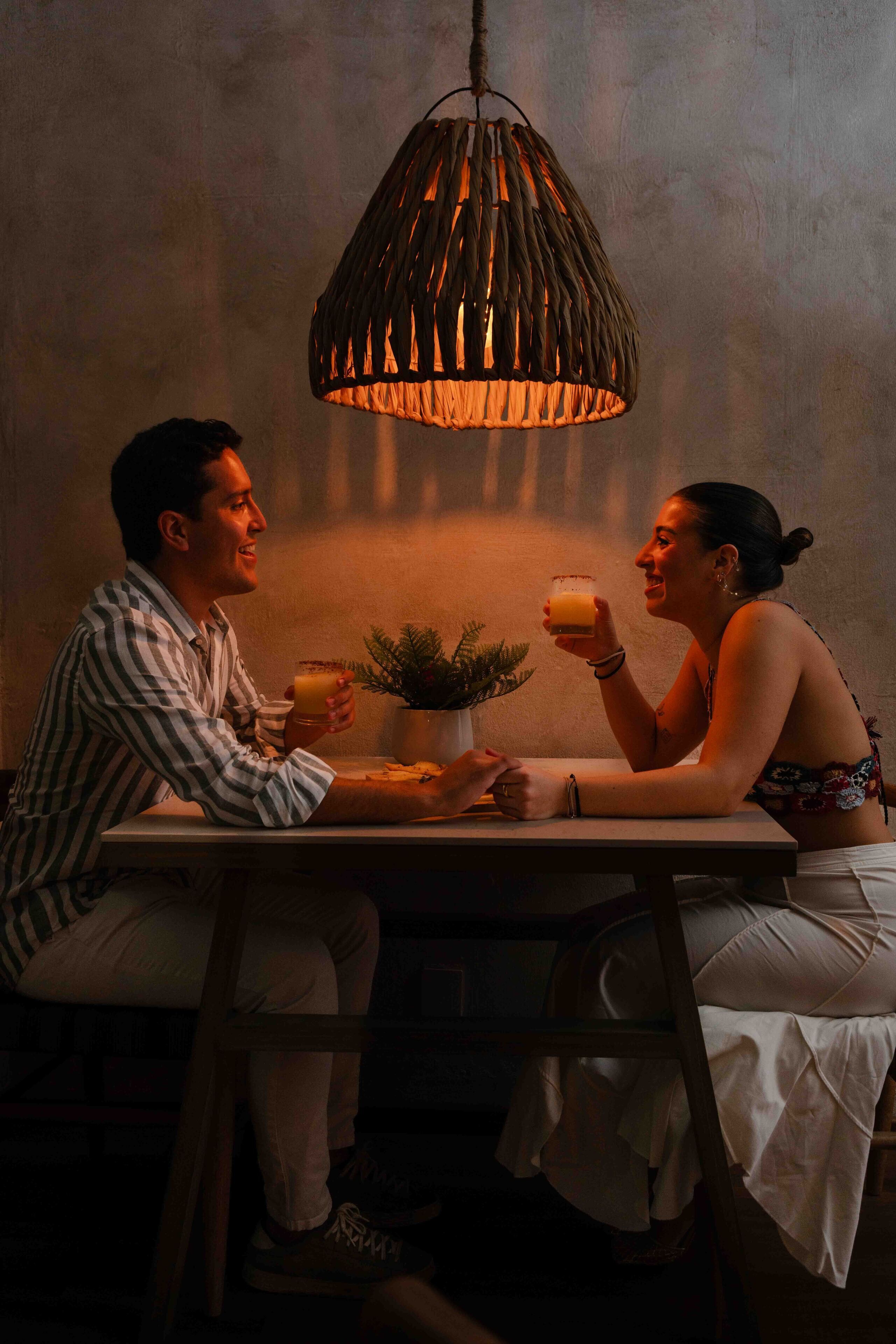 A couple sitting at a table with a hanging light fixture above them.