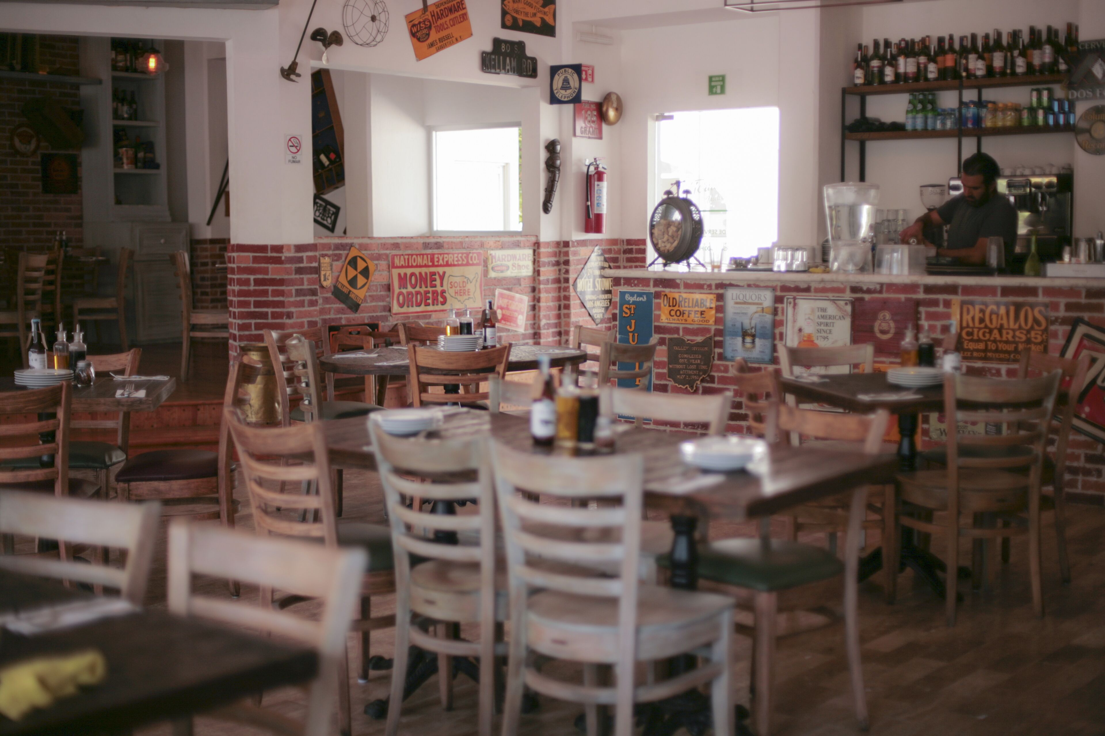 A restaurant with brick walls, wooden tables and chairs, and various signs and decorations.