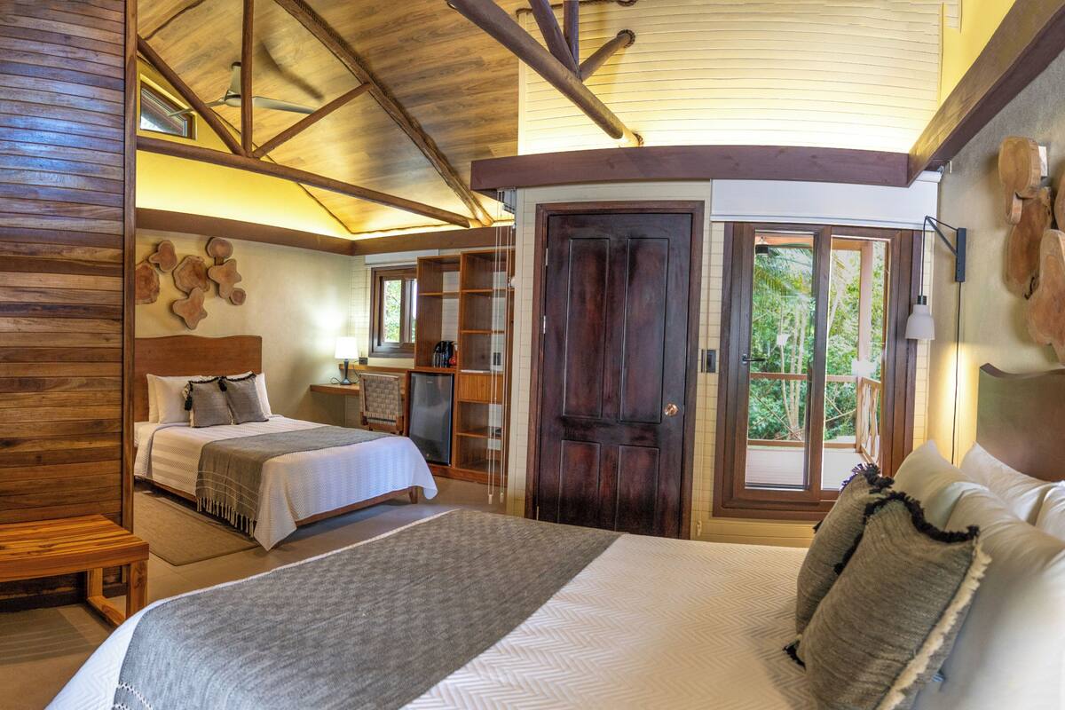 Une chambre spacieuse avec un grand lit, un plafond en bois et une vue sur l’extérieur grâce à une porte coulissante.