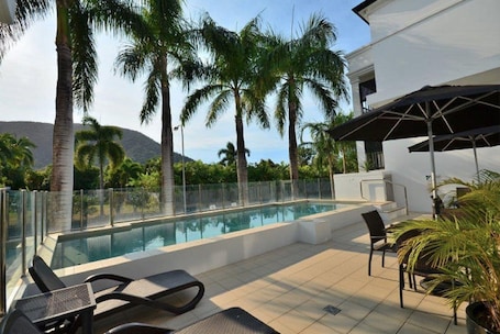 Una piscina al aire libre, sillones reclinables de piscina